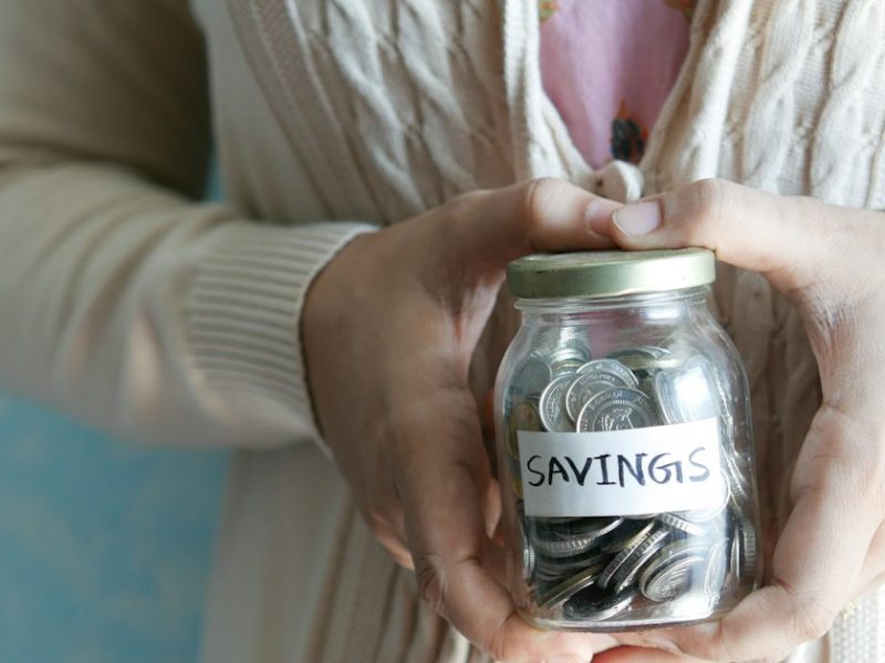 Женщина держит банку с надписью Savings — финансовая подушка безопасности