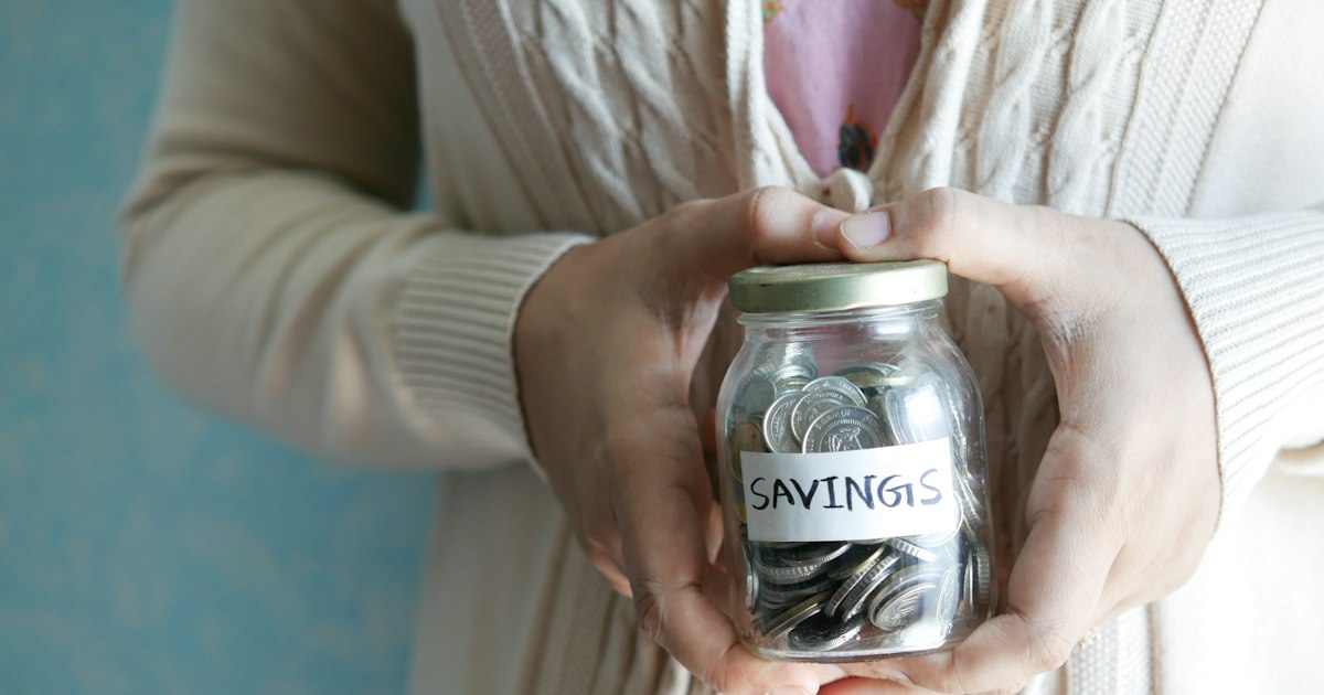 Женщина держит банку с надписью Savings — финансовая подушка безопасности